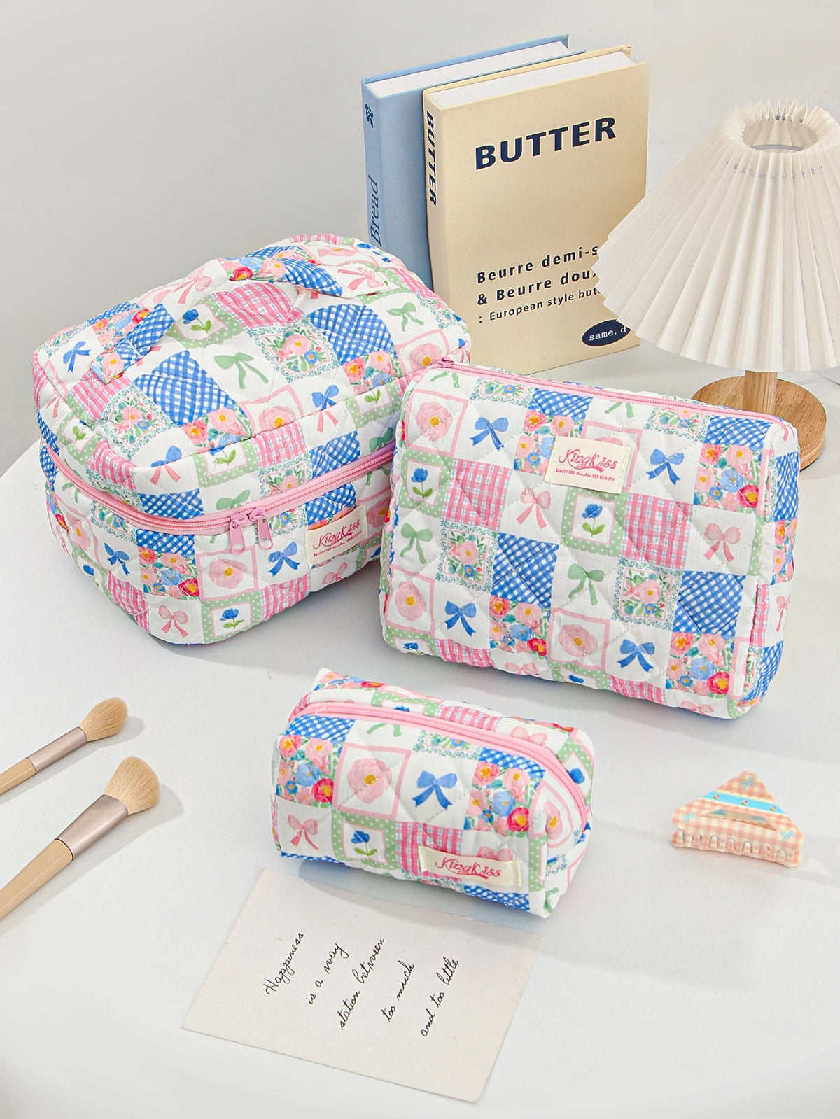 A pink and blue patchwork quilted makeup bag next to a butter-themed book.