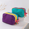 A vibrant lightweight travel makeup bag featuring purple, teal, and yellow accents.