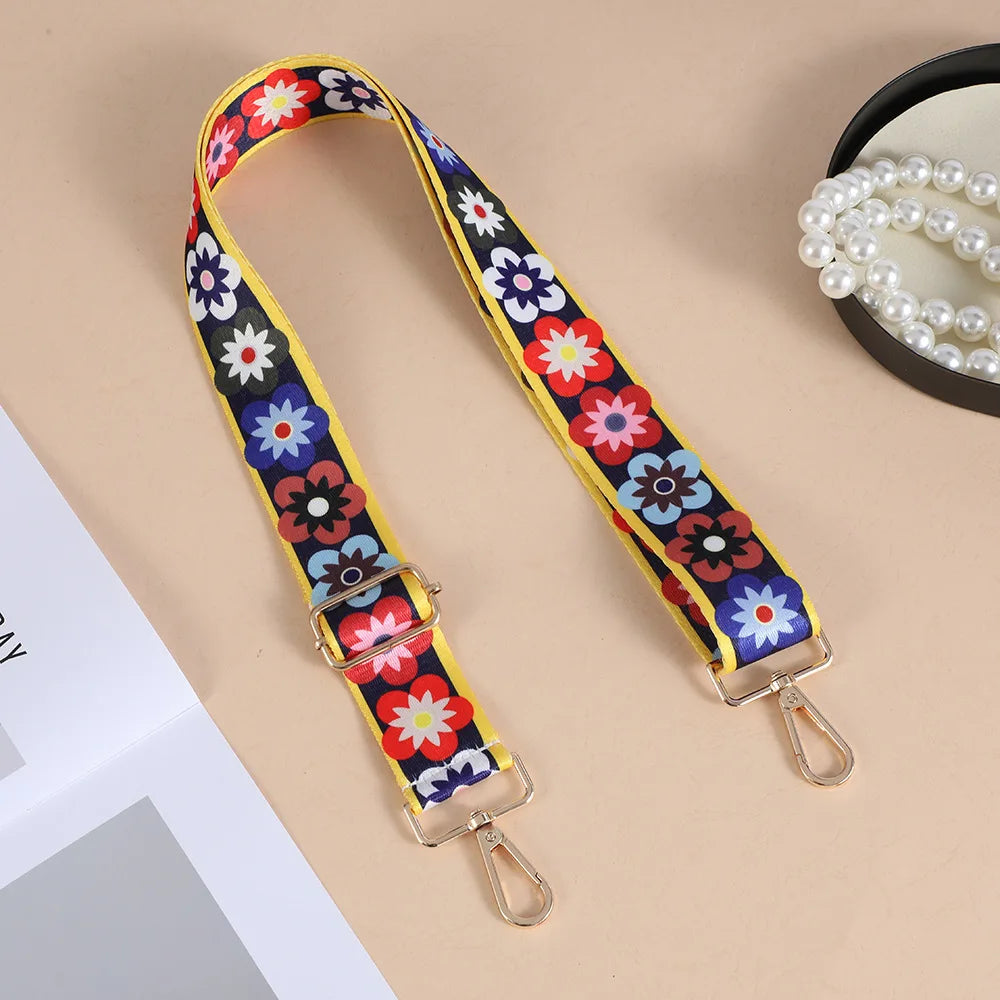 A yellow and purple floral patterned nylon crossbody bag strap with metal buckles.