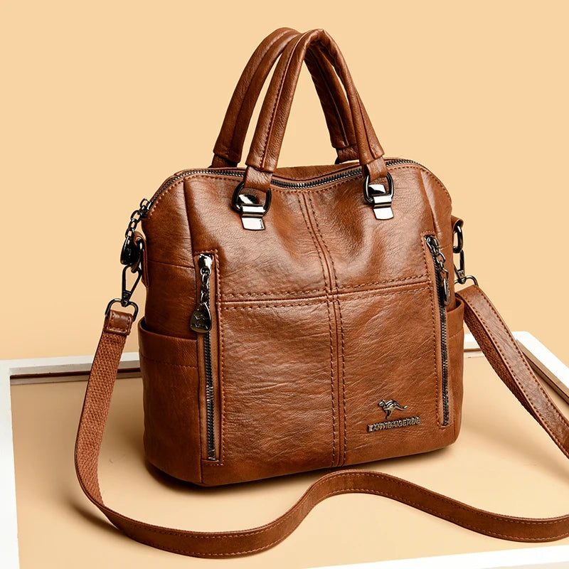 A brown leather fashionable crossbody backpack bag with silver hardware shown against a light background.