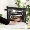 Una mano sostiene una bolsa de almacenamiento con cremallera de lona negra etiquetada como Cargadores y Cables, apoyada sobre