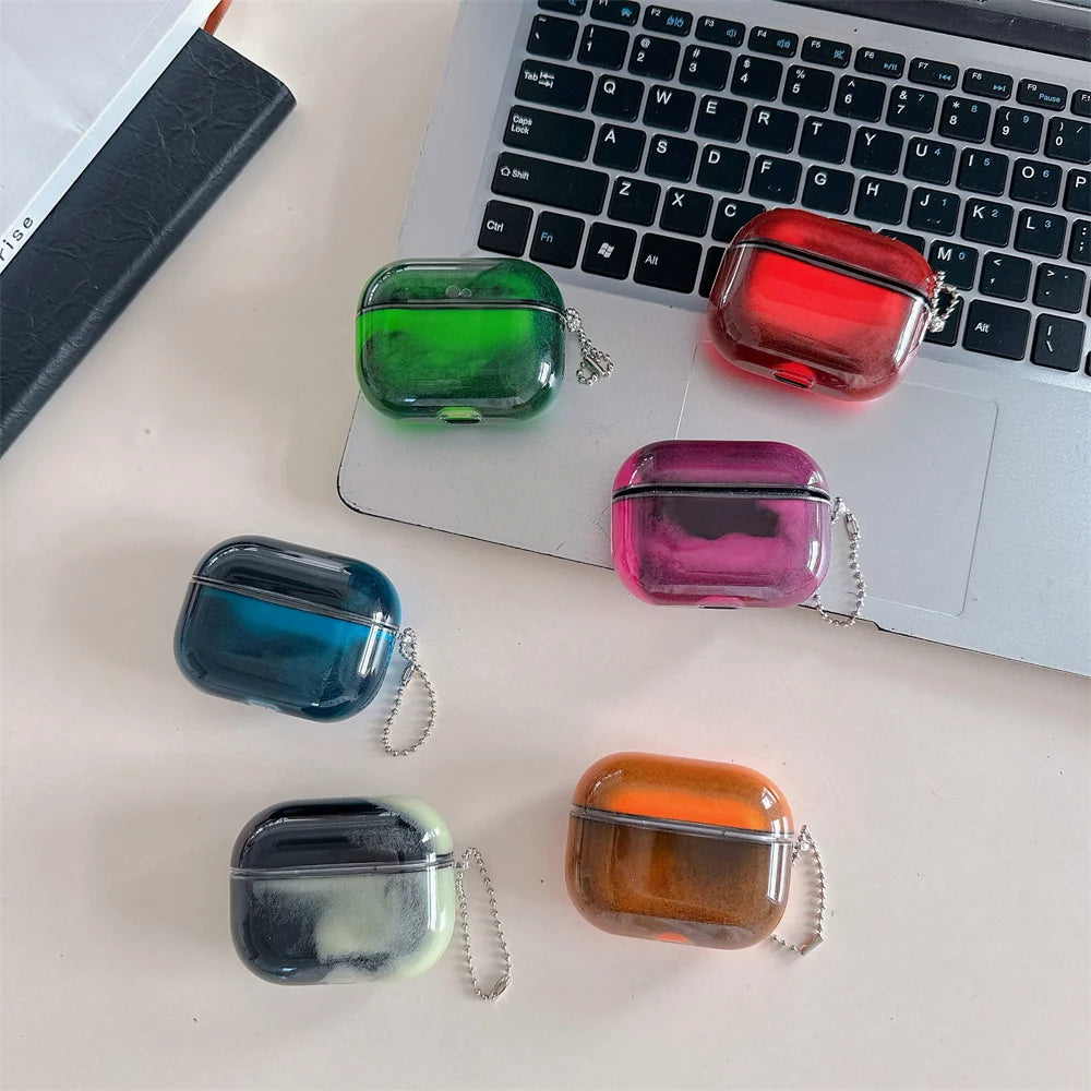 A collection of colorful luminous sand effect earphone cases resting on a laptop keyboard.