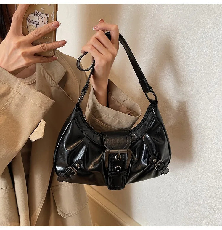 Nahaufnahme einer schwarzen Y2K-Retro-plissierten Schultertasche, die von einer Person vor einem hellen Hintergrund gehalten 