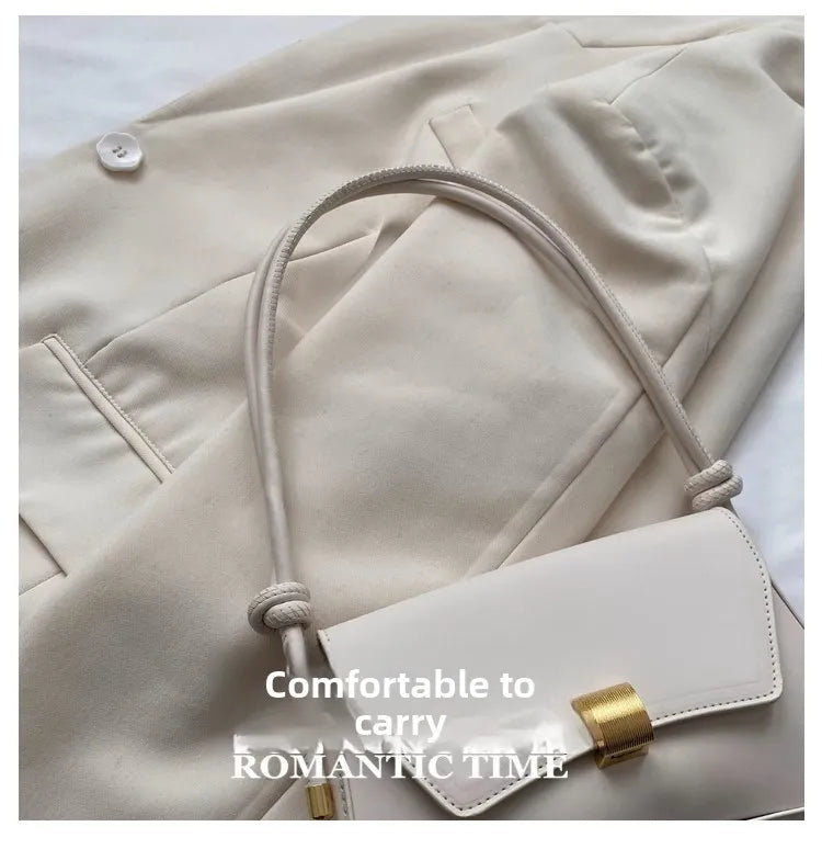 A light beige leather crossbody bag with a woven strap and gold hardware shown against a neutral background.