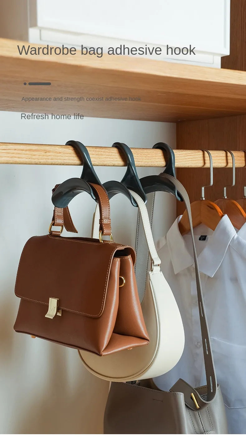 Eine braune Lederhandtasche hängt an einem Klebeflansch in einem Holzschrank neben anderen Taschen und Haken.