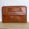 A brown leather crossbody clutch bag with a flap closure and stitching.