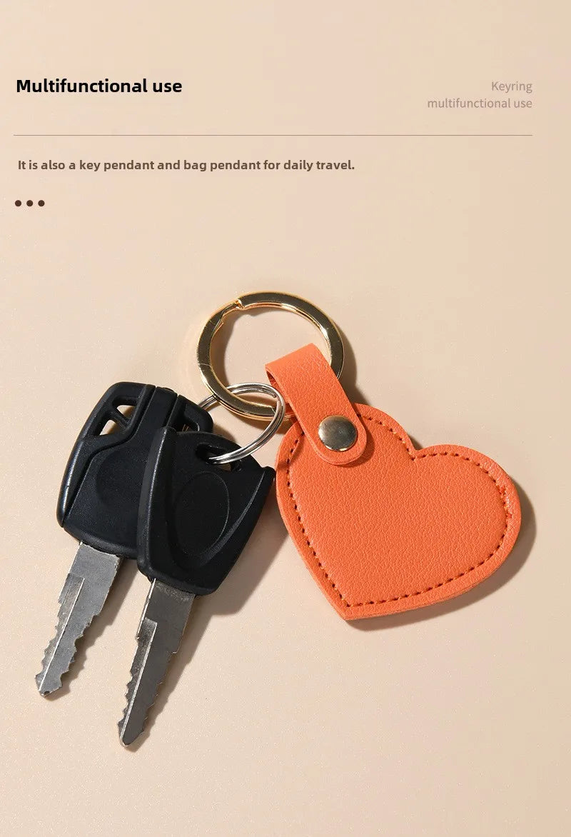 A set of keys attached to an orange leather heart pendant keychain.