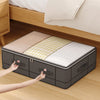 A foldable under-bed storage box with a window is shown on a wooden floor next to a bed.