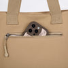 A beige canvas tote bag with tan straps and a zippered pocket featuring a phone holder.