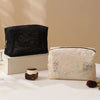 A black lace mesh cosmetic and jewelry organizer bag resting on a light wooden box.