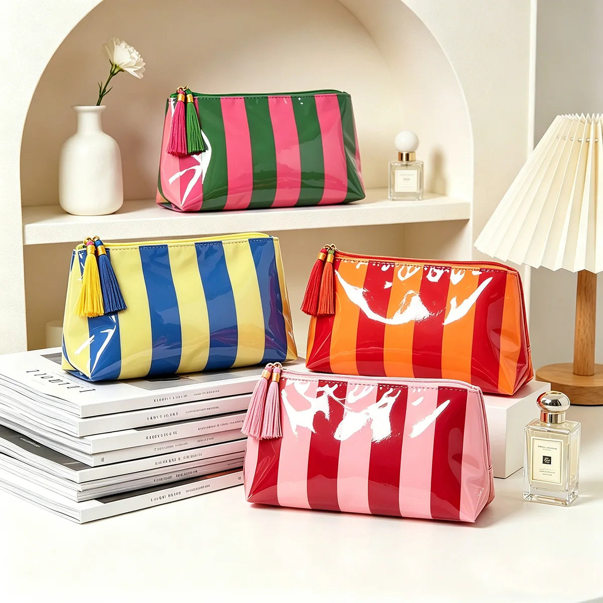 A collection of colorful striped cosmetic travel pouches in pink, green, yellow, and red with fringe displayed on a shelf.