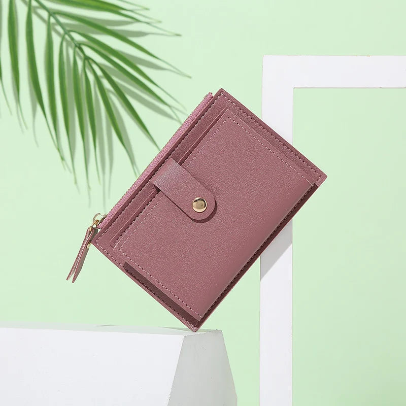 A mauve PU leather mini card holder wallet with a gold zipper is displayed against a light green background.