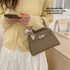 A woman wearing a yellow sweater and white skirt holds an elegant taupe PU leather crossbody clutch bag.