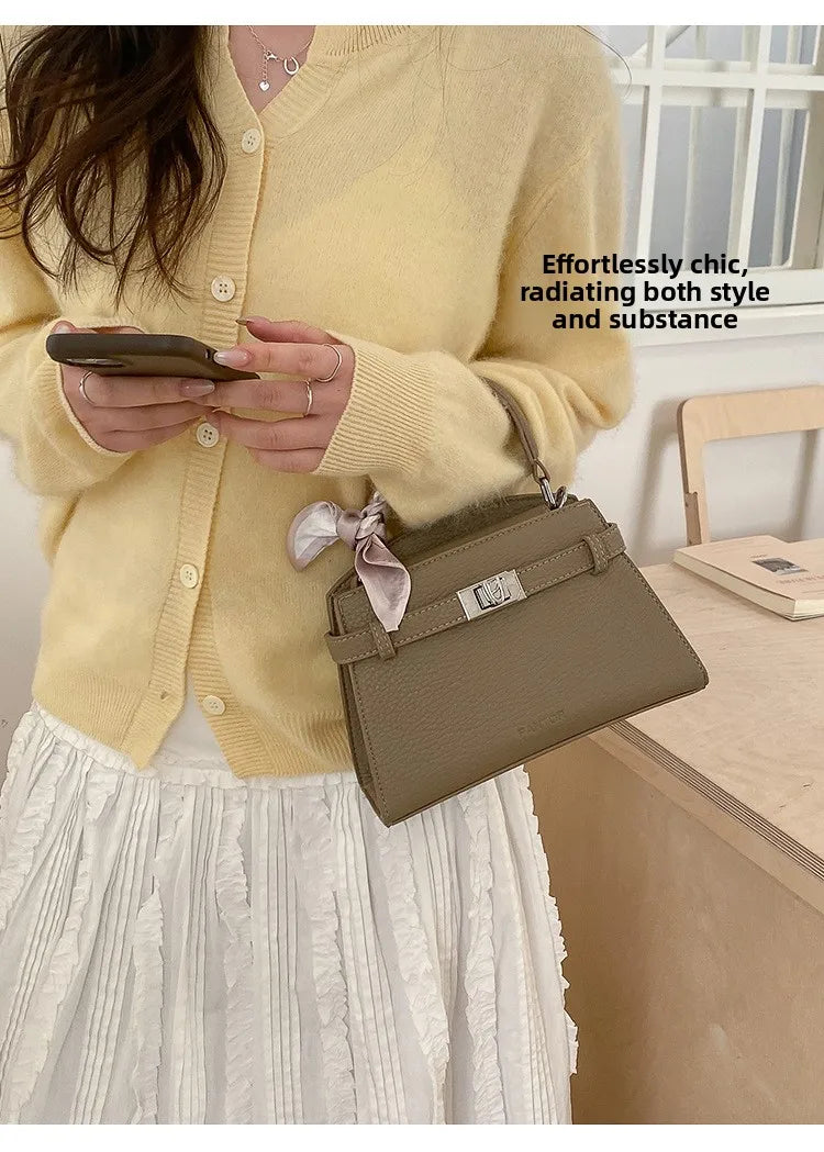 A woman wearing a yellow sweater and white skirt holds an elegant taupe PU leather crossbody clutch bag.