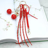 Red cherry charm bag keychain featuring a gold-colored braided rope and dangling charms.