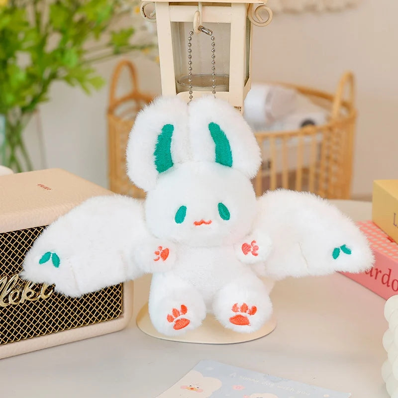 A white bat bunny plush toy with green accents is displayed on a light surface.