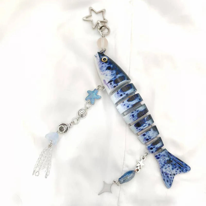 A blue and white fish charm with a silver star and blue accent details on a clear acrylic keychain.
