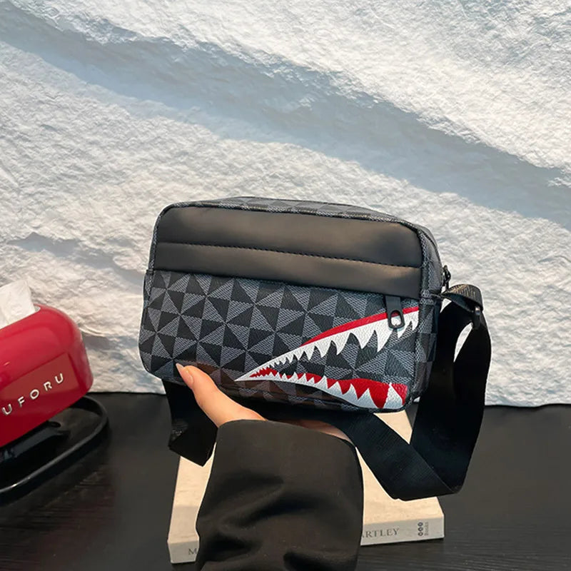A black and gray patterned crossbody coin purse and mobile phone bag being held by a person against a white background.