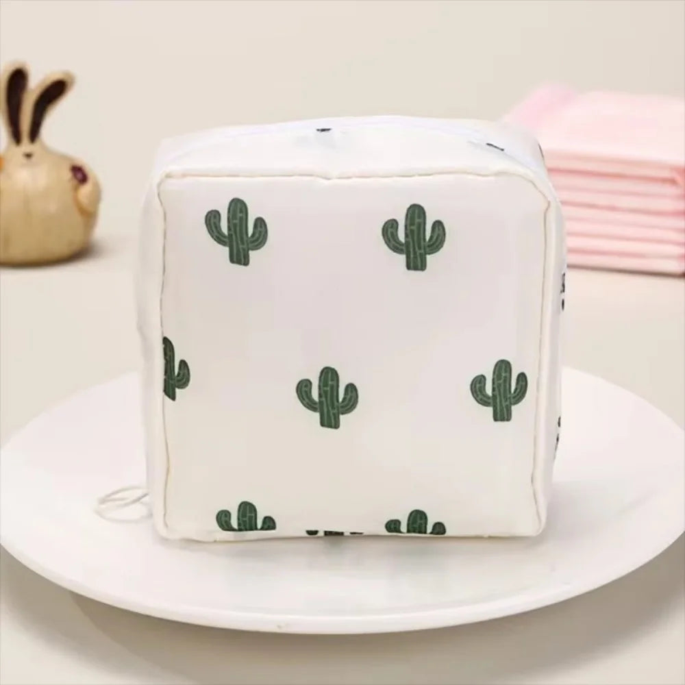 A white fabric pouch with a repeating green cactus pattern, resting on a white plate.