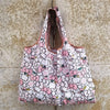 A pink and white patterned reusable shopping bag is displayed against a textured background.