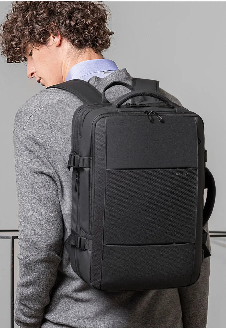 A man wearing a grey sweater is shown from the back, carrying a black men's business travel backpack.
