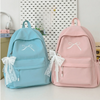 A light blue embroidered backpack and a pink embroidered backpack are displayed on a white surface.