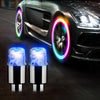 A pair of blue LED tire valve stem lights are shown next to a dark car with illuminated rims.
