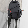 Un sac de sport pour homme gris foncé est tenu par une main contre un vêtement gris clair.