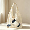 A cream-colored knitted tote bag with a blue elephant design, shown against a light background.