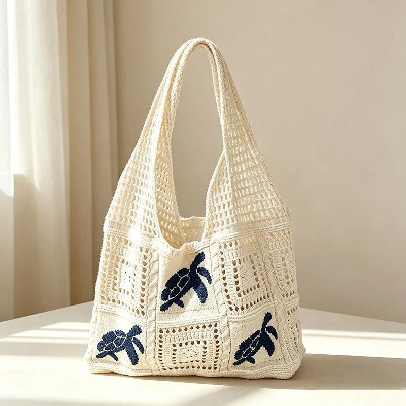 A cream-colored knitted tote bag with a blue elephant design, shown against a light background.