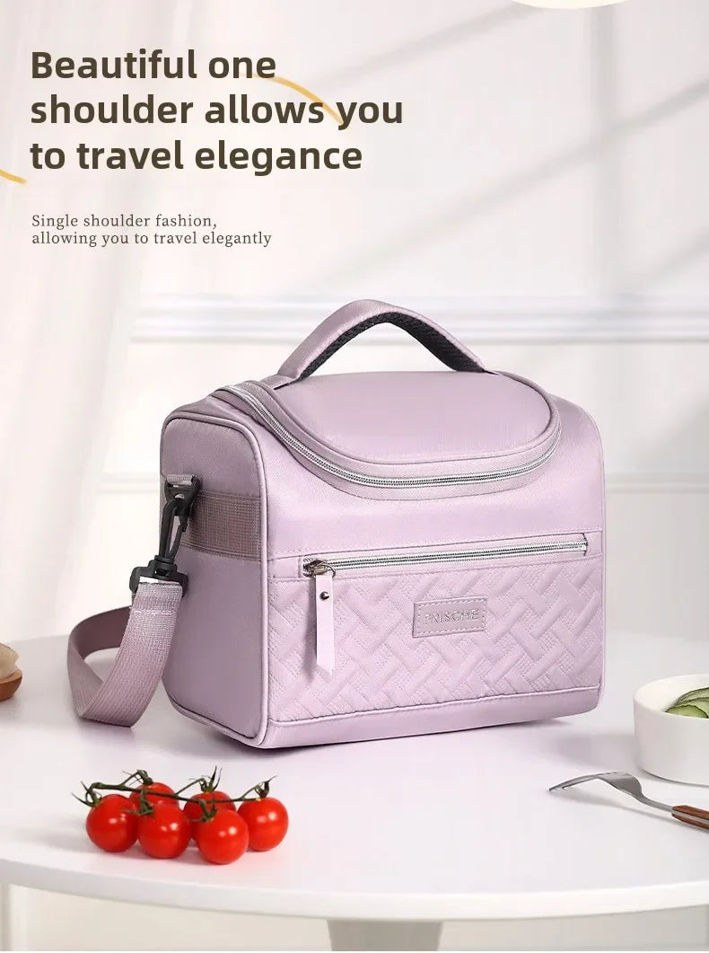 Bolsa térmica lavanda con correa acolchada mostrada sobre una mesa blanca.