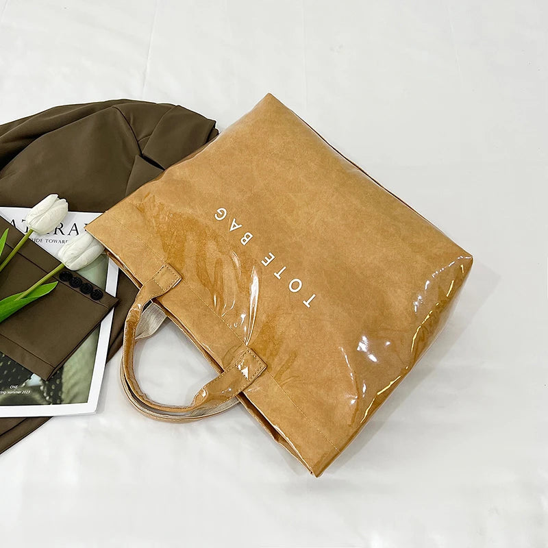 Una bolsa de tela de PVC minimalista color marrón junto a un artículo de tela verde oliva oscuro.