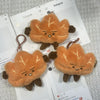 A set of cute maple leaf plush keychain bag charms in various shades of orange and brown.