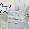 Light blue quilted cosmetic storage pouch with white lace trim resting on a stack of Barton Springs books.