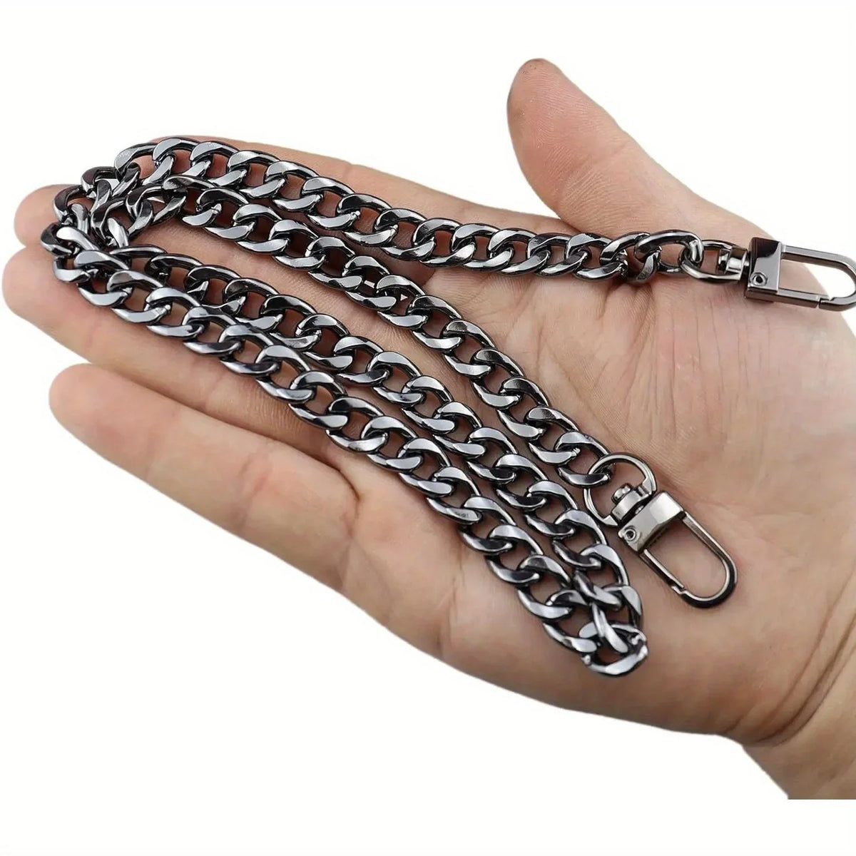 A hand holds a silver metal chain strap for handbags and wallets.