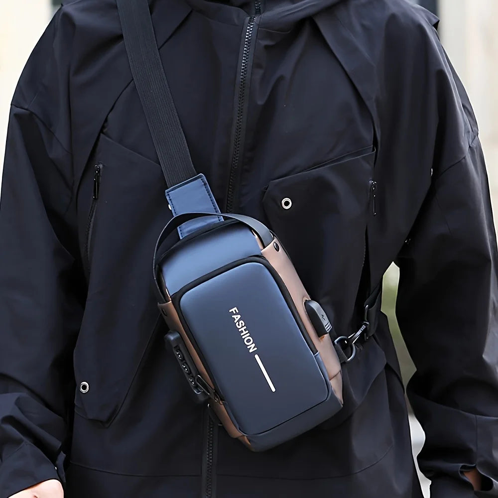 A dark gray oxford sling chest bag with a brown leather strap is worn on a black jacket.