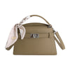 A beige PU leather crossbody clutch bag with a braided strap and silver hardware.