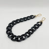 A black acrylic chain bracelet with gold-colored clasps.