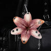 A realistic pink orchid flower keychain attached to a black leather bag.