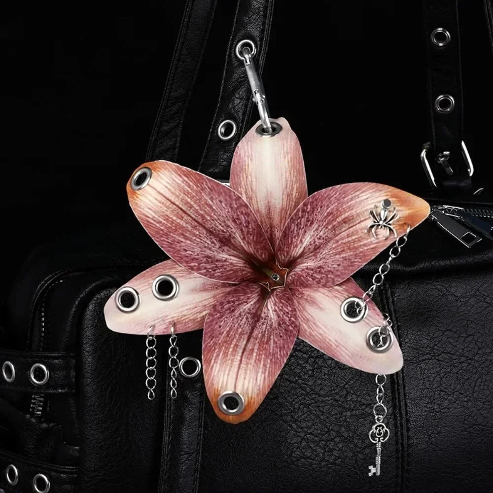 A realistic pink orchid flower keychain attached to a black leather bag.