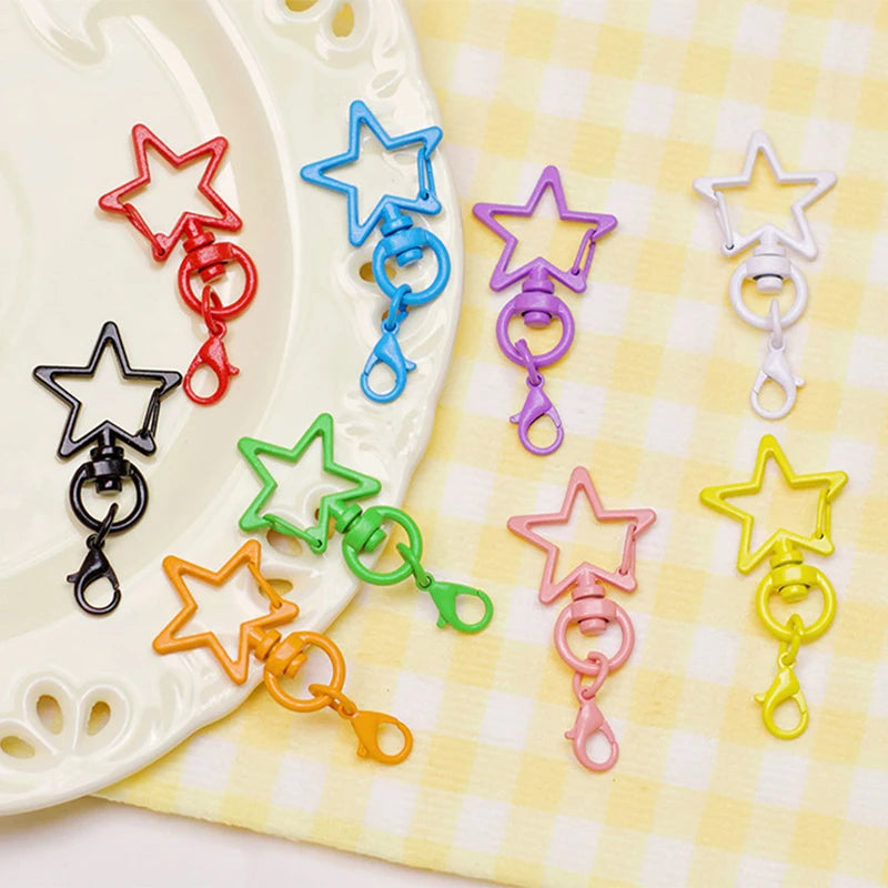 Assorted metal keychain clasp set featuring various star shapes and colorful rings on a yellow checkered cloth.