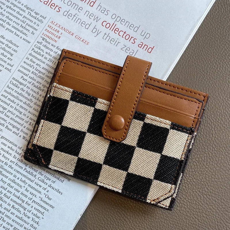 A brown and black checkered PU leather mini card wallet resting on a light-colored surface.