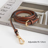 A brown leather strap with a gold buckle is displayed on a box, showing its adjustable length.