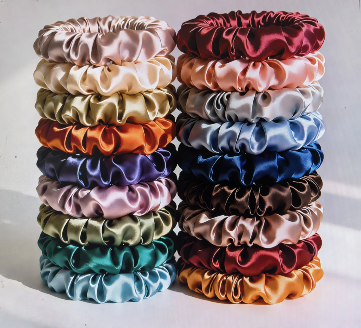 A stack of 19 thin scrunchies hair ties in various shades of pink, purple, green, and blue.