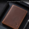 A brown genuine leather passport holder is shown resting on a dark surface next to a pen.
