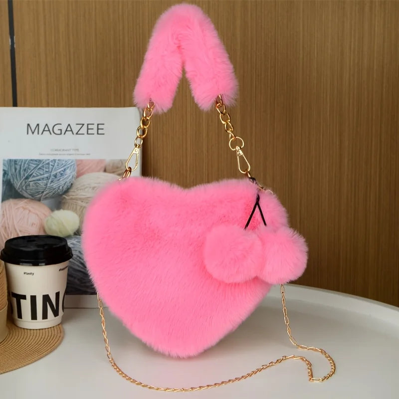 A bright pink faux fur heart shaped crossbody purse with gold chain details.