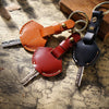 A genuine leather key fob cover with a keychain ring, featuring brown and dark red leather accents.