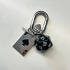 A silver keychain set featuring a padlock and a black and white die.