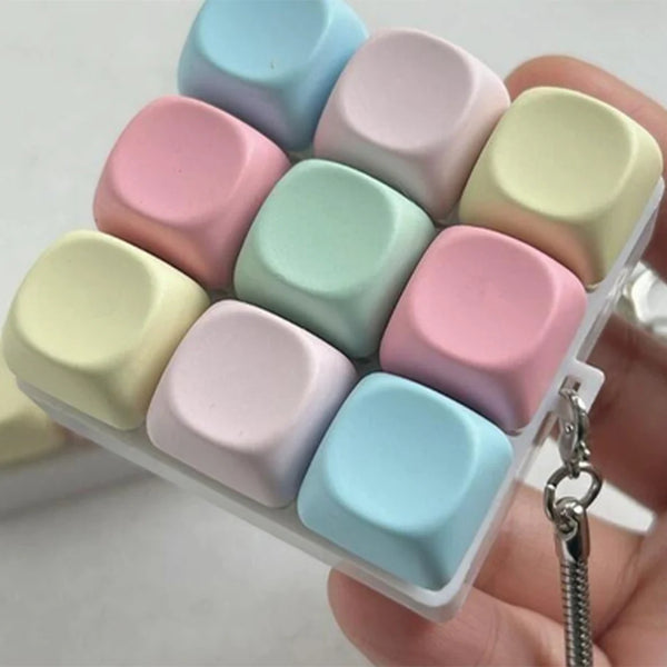 A collection of colorful silicone macaron-shaped fidget keyboard keychains arranged in a square pattern.