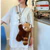 A person is wearing a white t-shirt featuring a white butterfly design and holding a brown red panda plush toy.